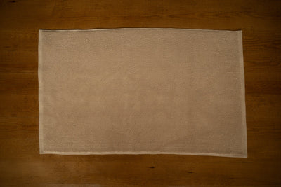 Beige textured bathmat on a wooden floor
