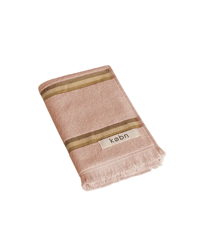Warm pink hand towel with a tonal brown stripe, fringing and 'kobn' label on a white background