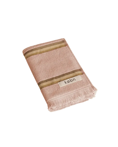 Warm pink hand towel with a tonal brown stripe, fringing and 'kobn' label on a white background