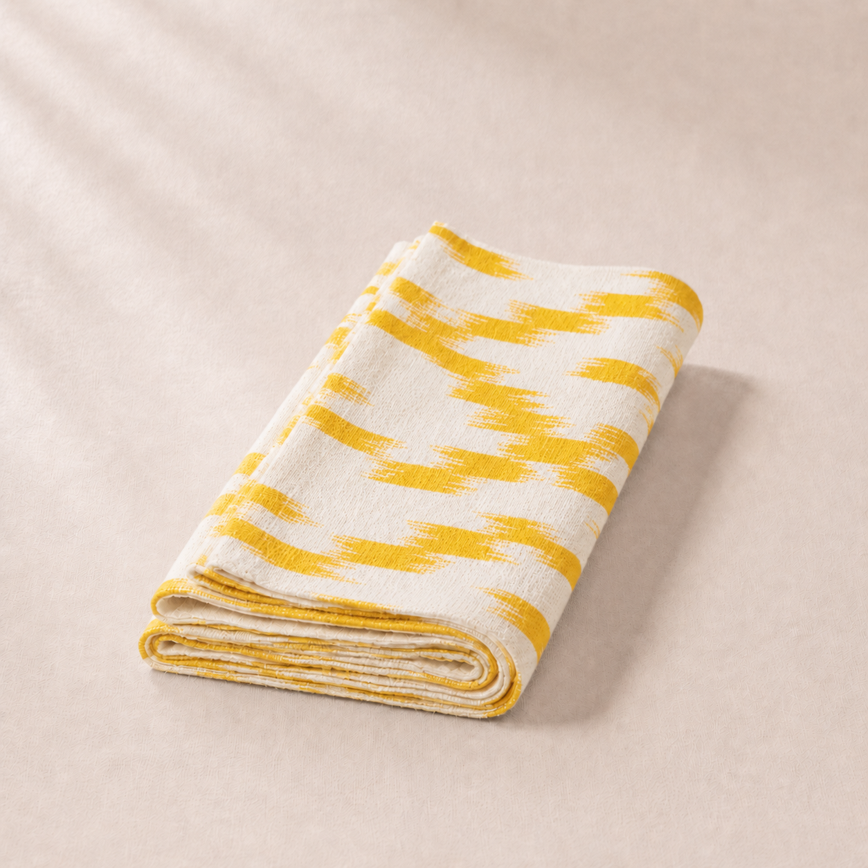 Folded yellow and white striped blanket on a beige background