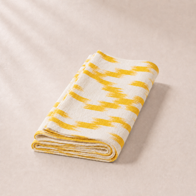 Folded yellow and white striped blanket on a beige background