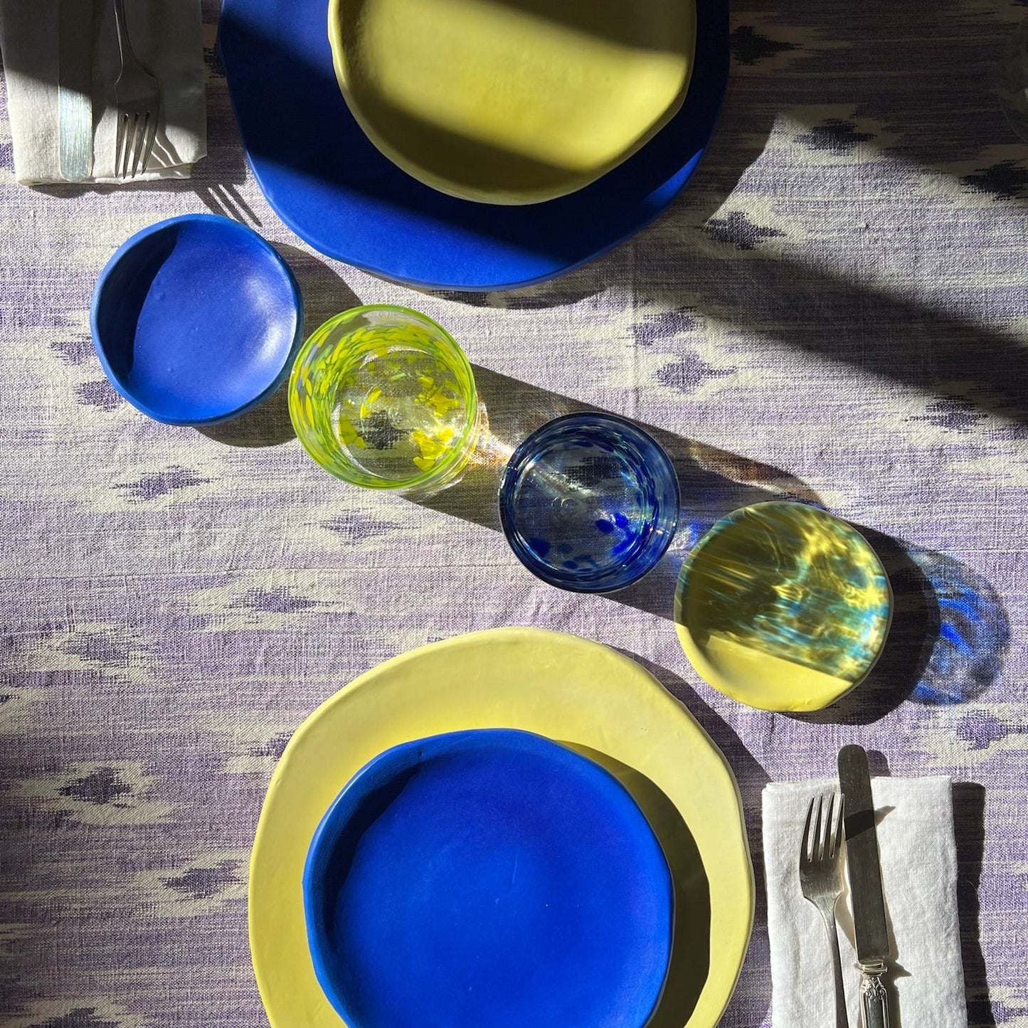 Colorful plates and glasses on a textured tablecloth - lifestyle