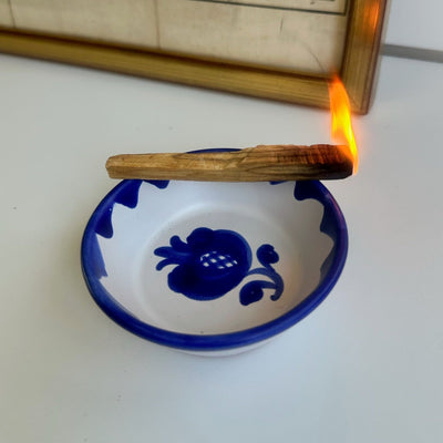 Candle being lit in a blue ceramic dish with an old map in the background - lifestyle