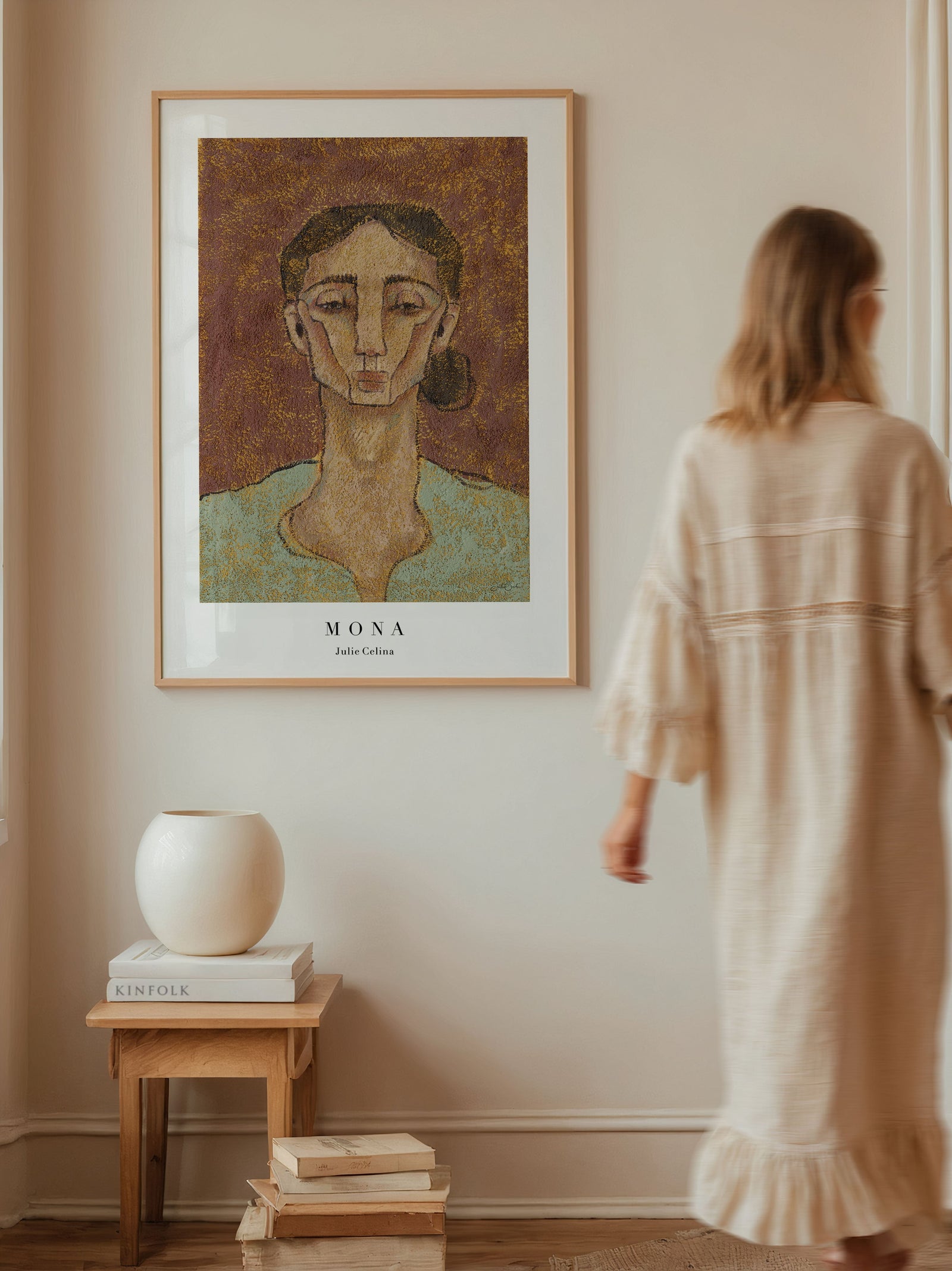 textured wall art print of a portrait of a soulful and quiet but strong woman with a brown background on a wall with a woman walking past it