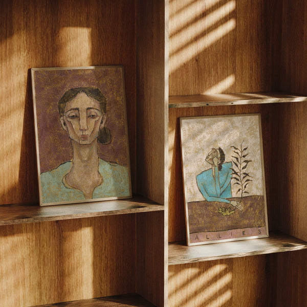 Two framed artworks of women in a textured look on wooden shelves with sunlight casting shadows.
