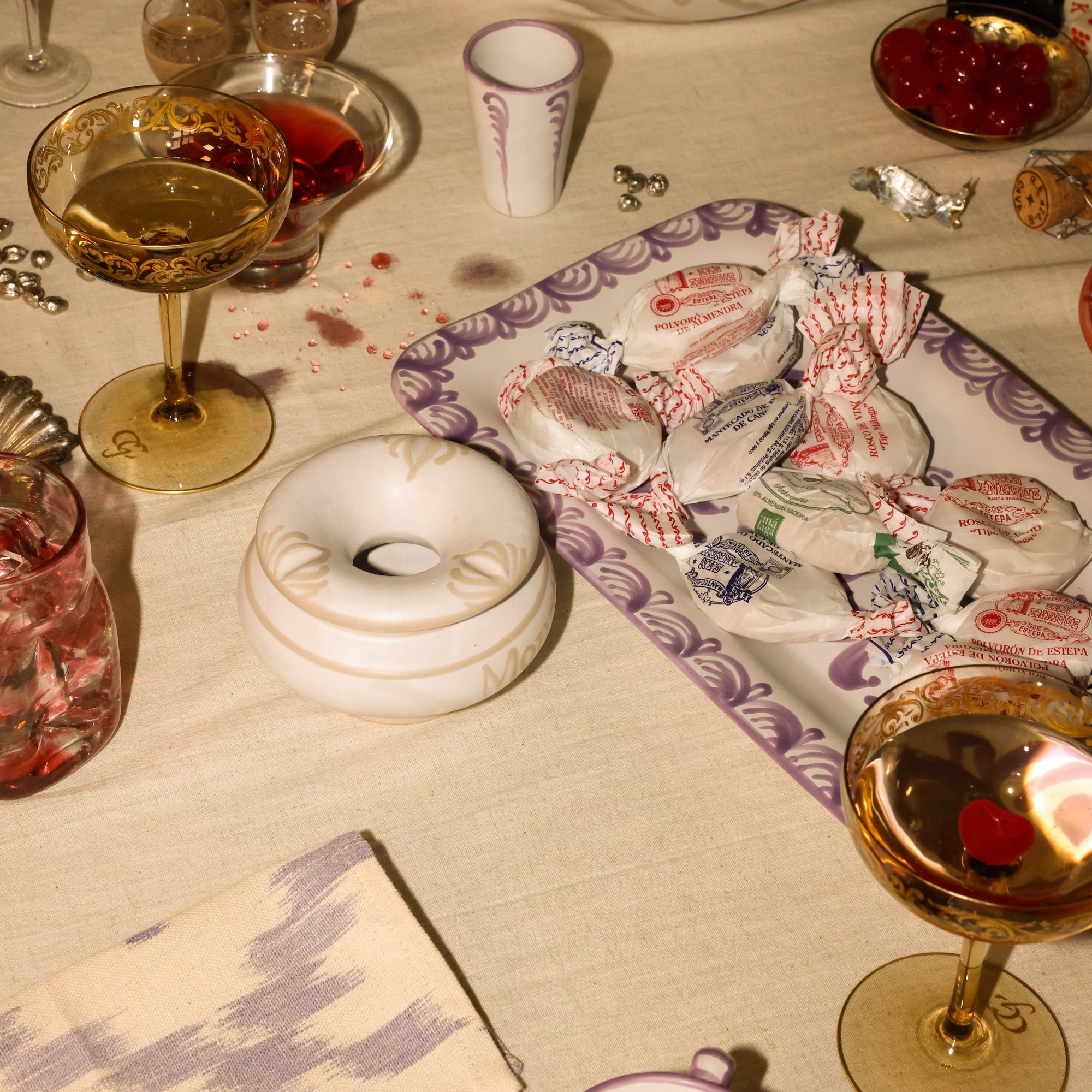 Table setting with wine glasses, a donut, and a box of tissues on a tablecloth. - lifestyle