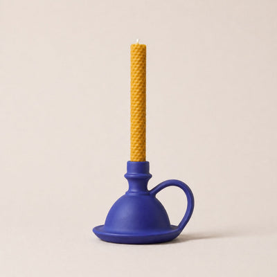 Blue plunger with a yellow candle on a beige background