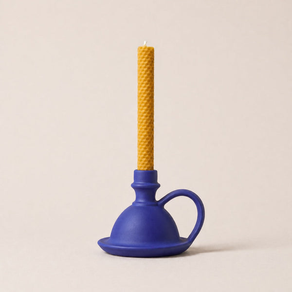 Blue plunger with a yellow candle on a beige background