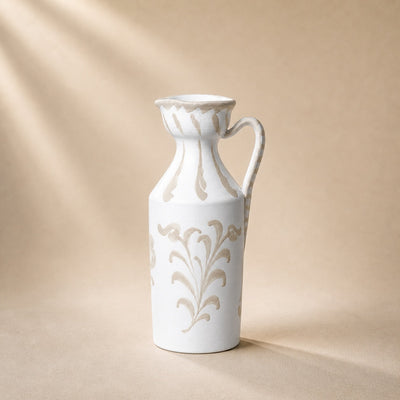 White ceramic pitcher with floral patterns on a beige background