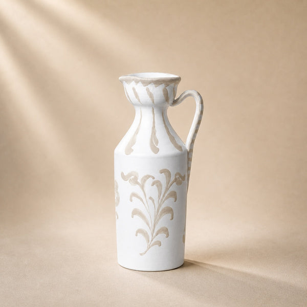 White ceramic pitcher with floral patterns on a beige background