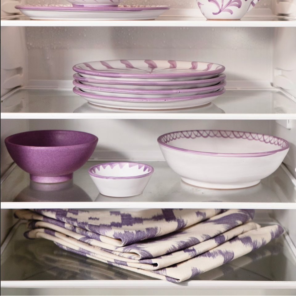 Purple and white ceramic dishes and tableware arranged on a refrigerator shelf. - lifestyle