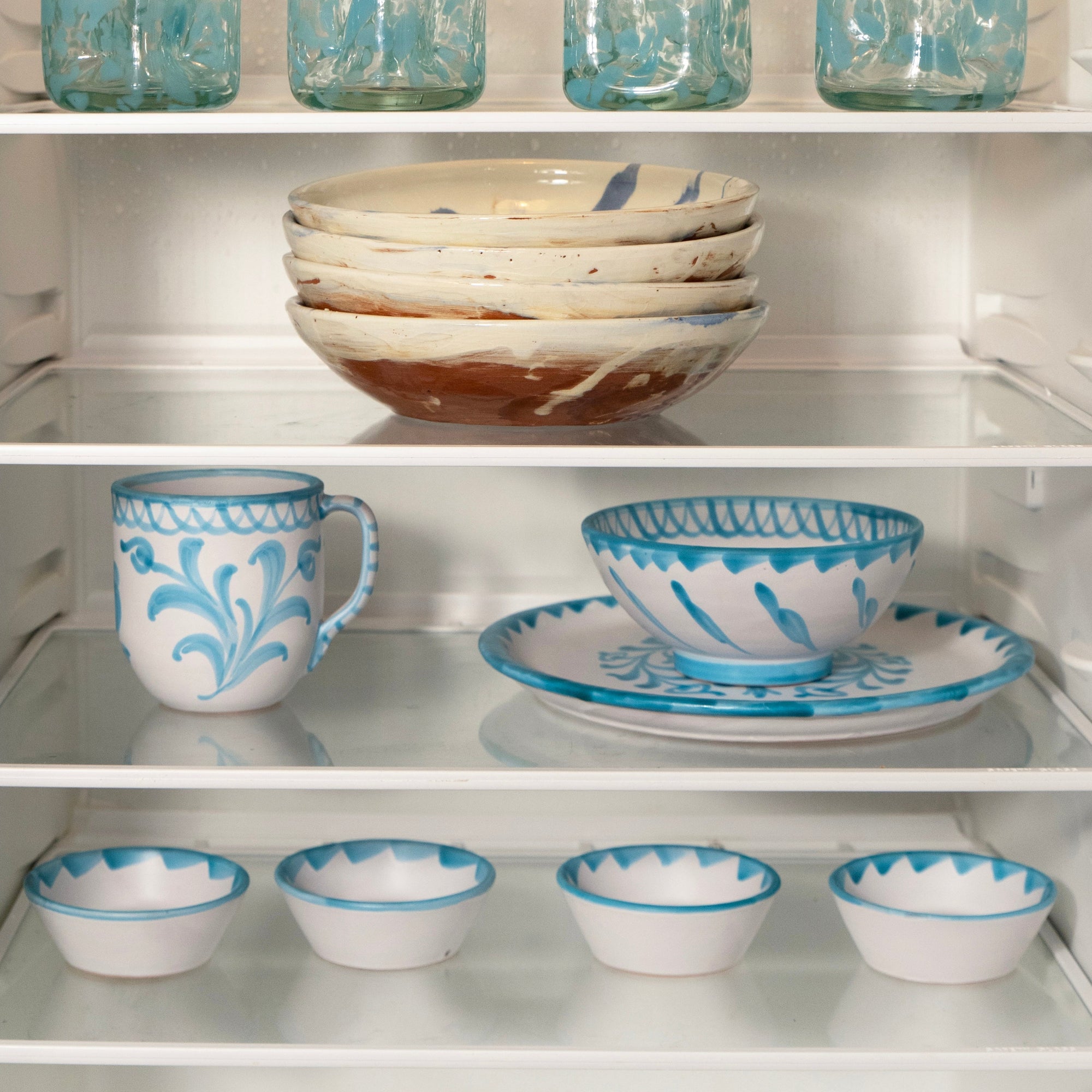 Ceramic and glassware with blue patterns on a white shelf - lifestyle