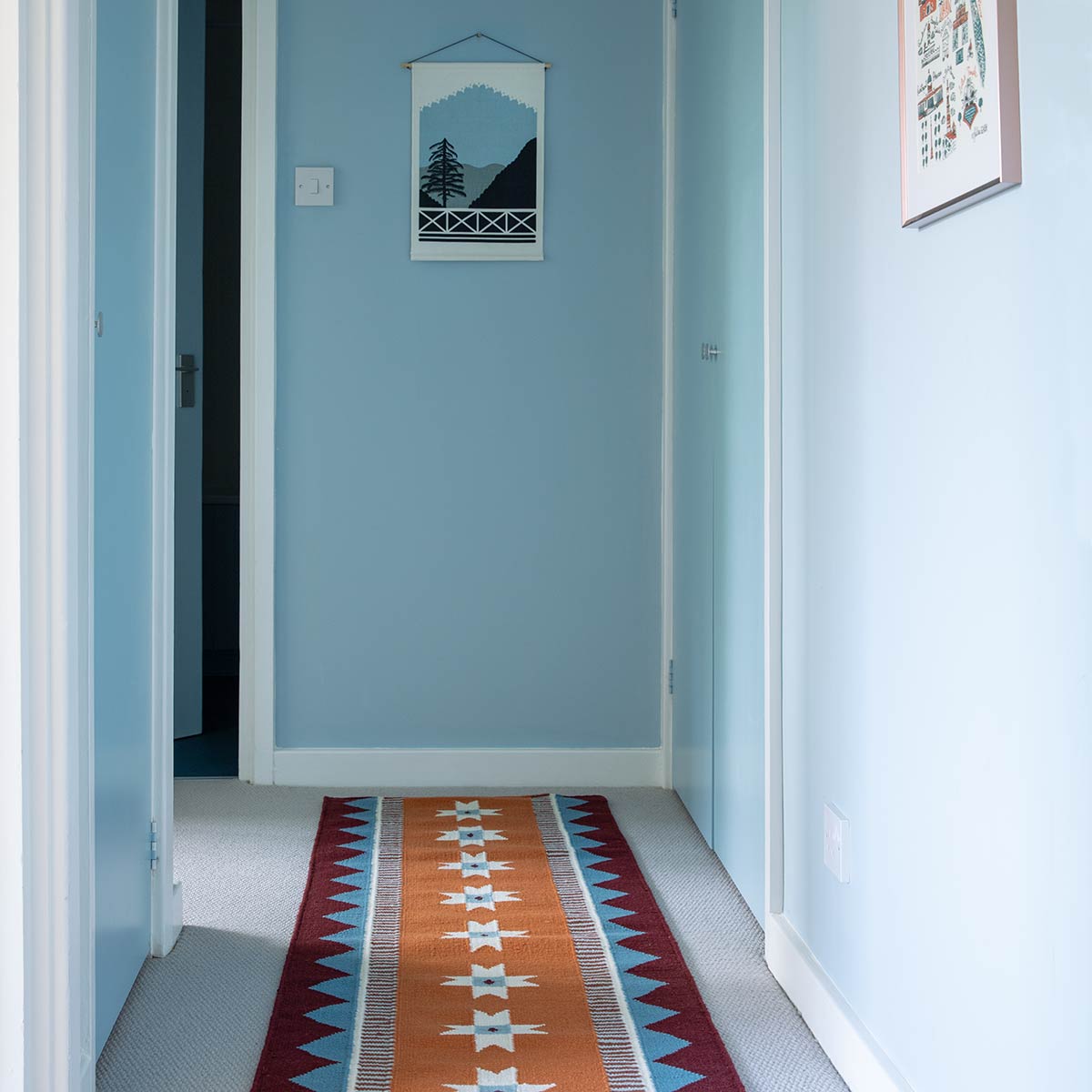 Light blue hallway with Orange geometric runner rug handwoven with blue accents. 