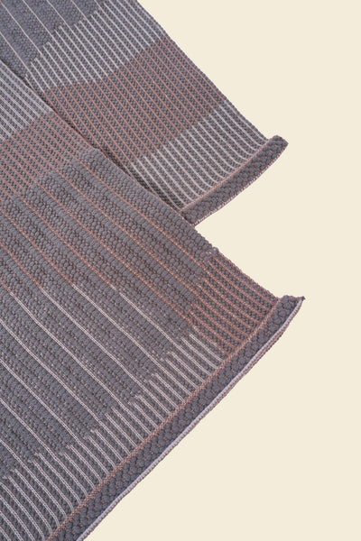 corner of beige knit organic cotton table mat with abstract design