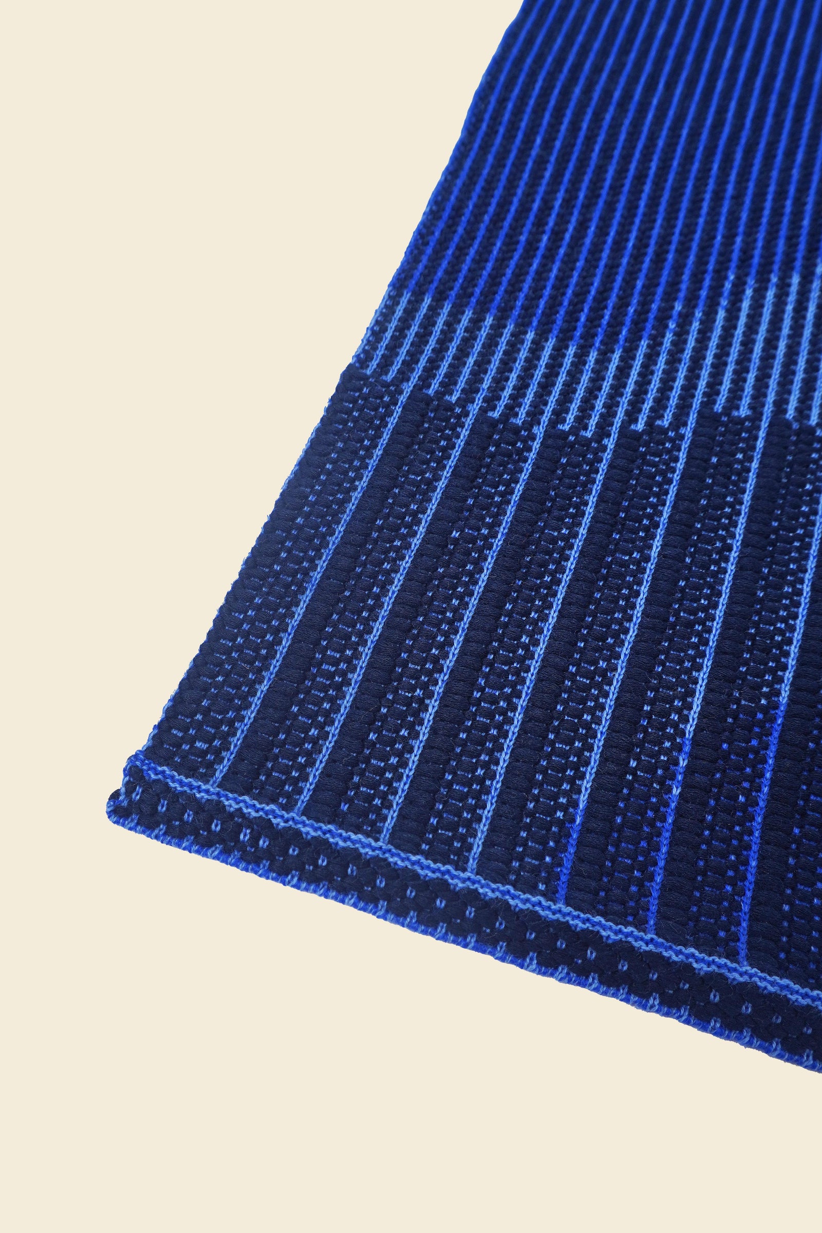 corner of blue knit organic cotton table mat with abstract design
