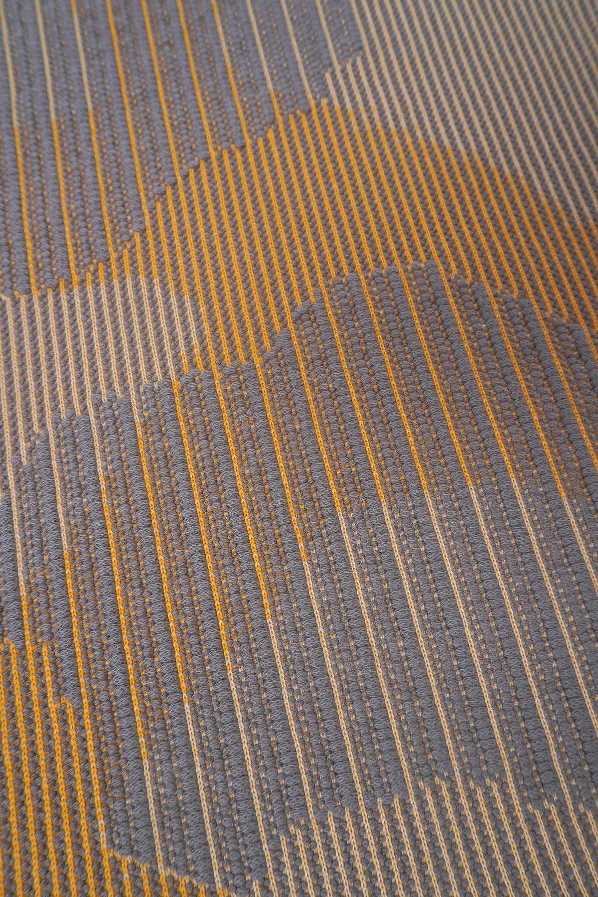 detail of yellow knit organic cotton table mat with abstract design