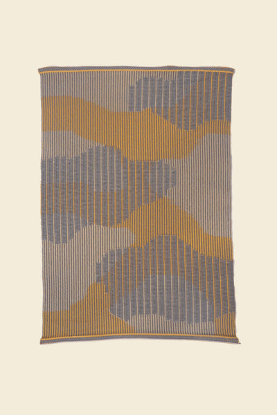 top view of yellow knit organic cotton table mat with abstract design on neutral background