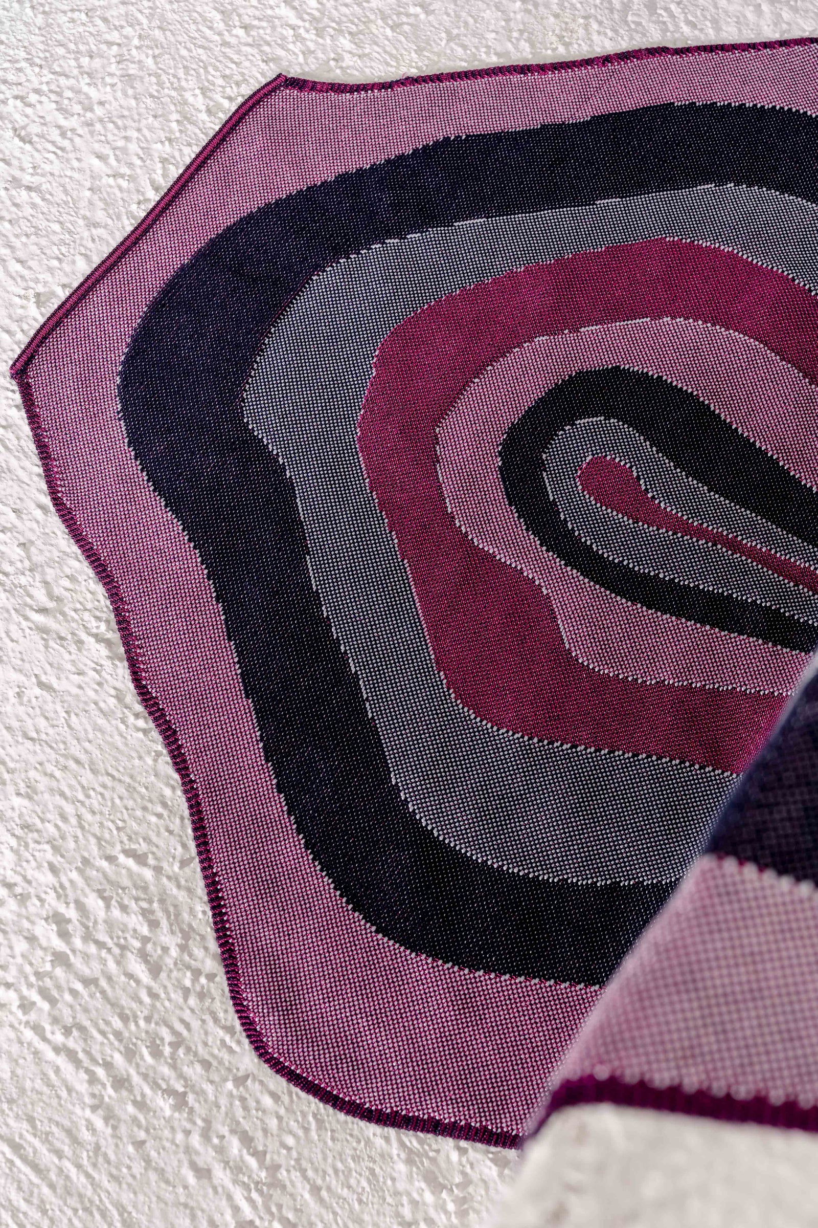 close-up of organic cotton knit tablecloth with curved edges in purple and navy