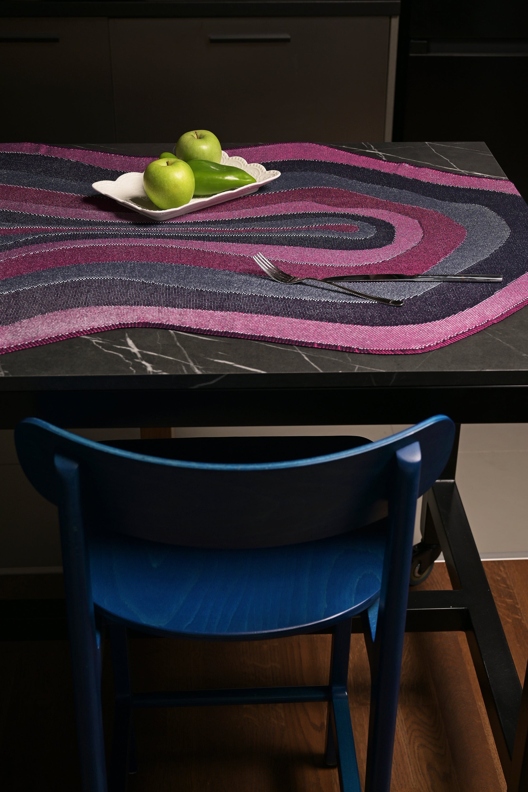 side view of organic cotton knit tablecloth with curved edges in purple and navy on table