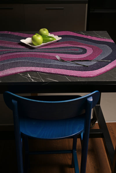 side view of organic cotton knit tablecloth with curved edges in purple and navy on table