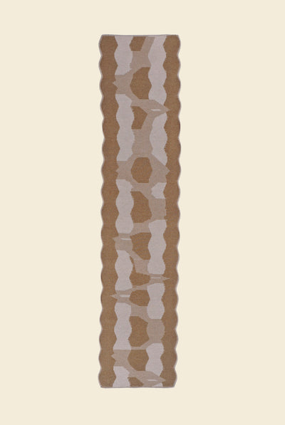 back side top view of beige knit organic cotton and viscose table runner with abstract pattern and wavy edges