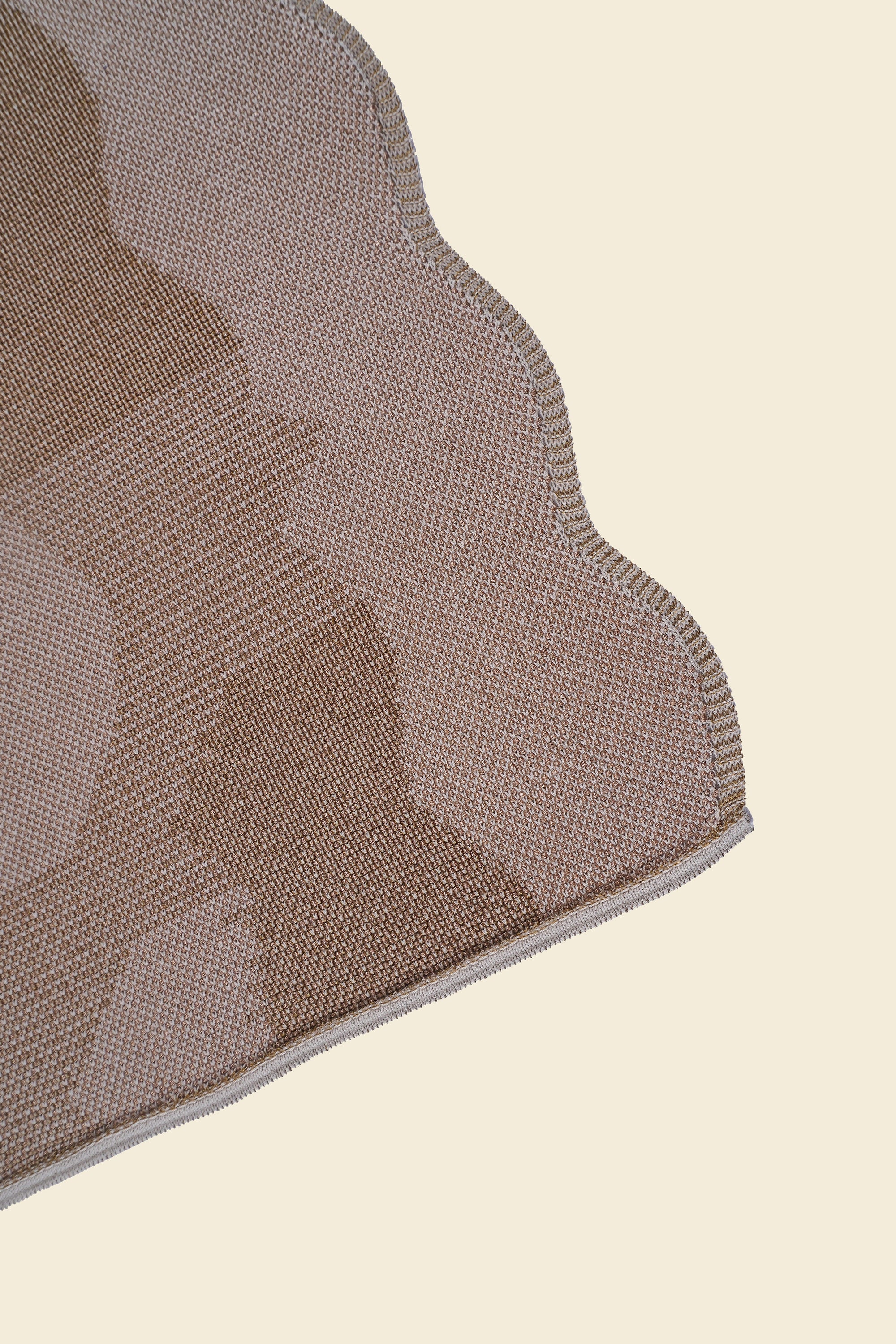 corner of beige knit organic cotton and viscose table runner with abstract pattern and wavy edges