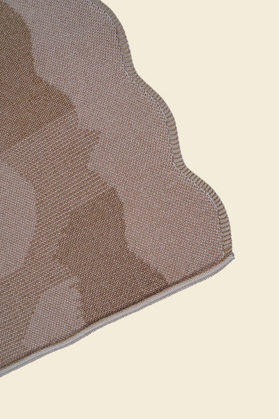 corner of beige knit organic cotton and viscose table runner with abstract pattern and wavy edges