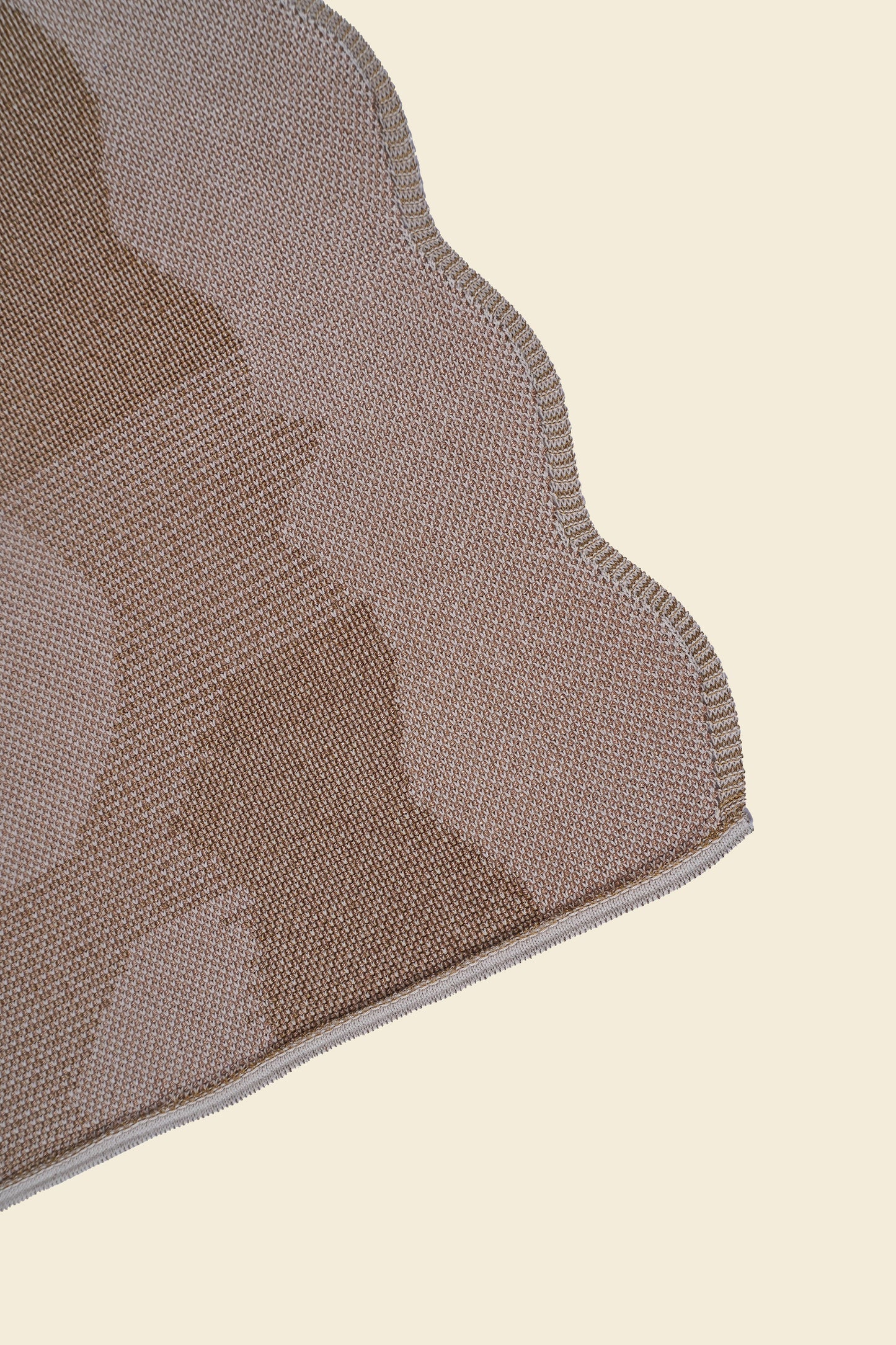 corner of beige knit organic cotton and viscose table runner with abstract pattern and wavy edges