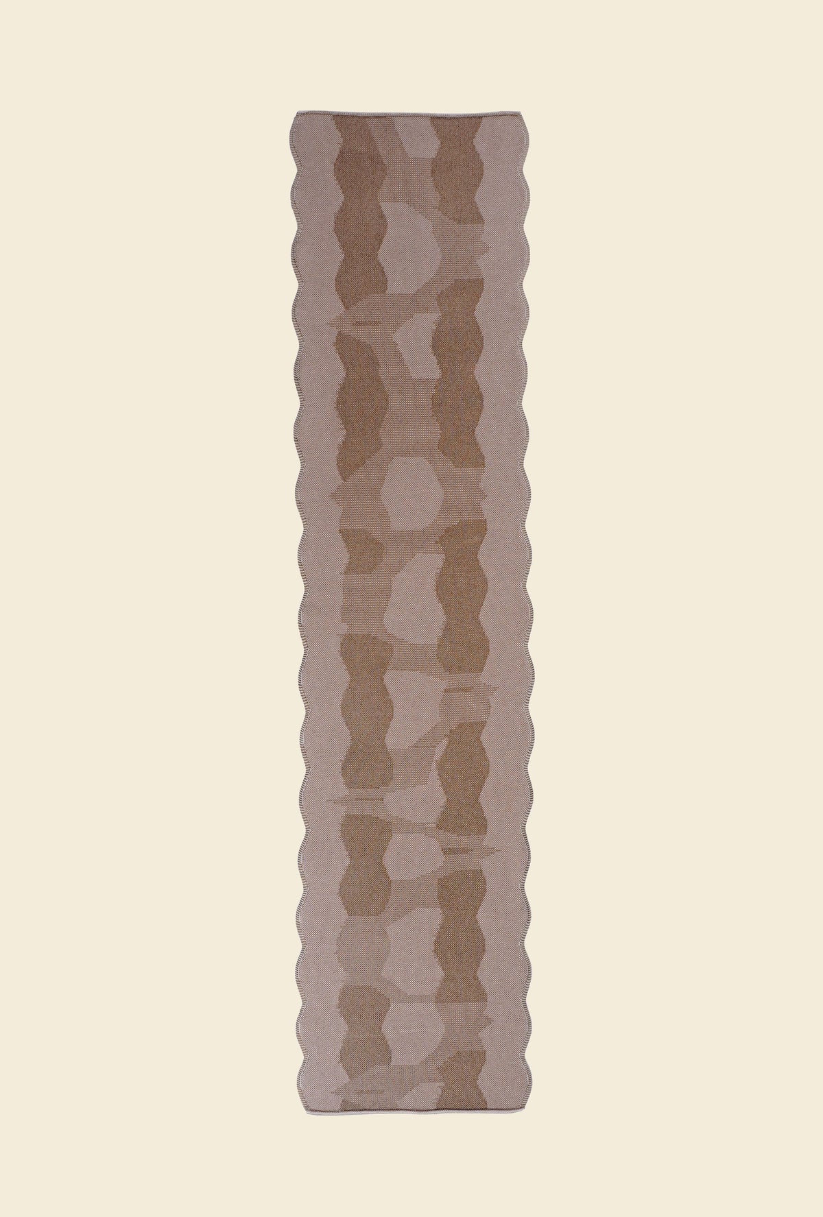 top view of beige knit organic cotton and viscose table runner with abstract pattern and wavy edges