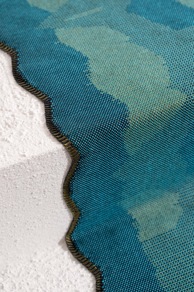 side detail of green knit organic cotton and viscose table runner with abstract pattern and wavy edges