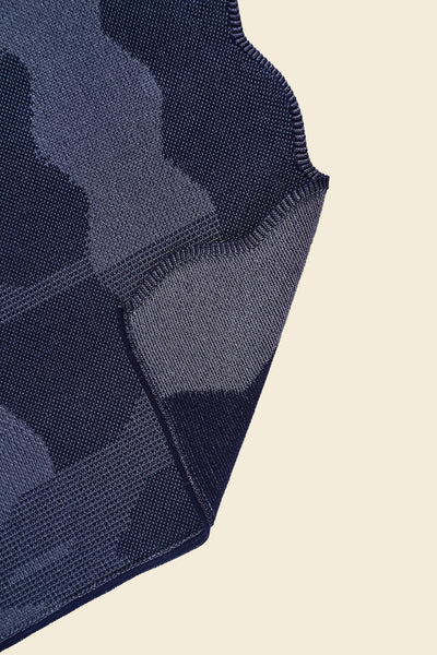 corner of grey knit organic cotton and viscose table runner with abstract pattern and wavy edges