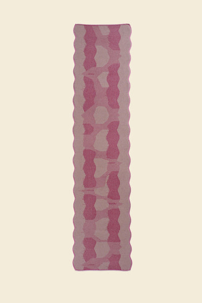 top view of pink knit organic cotton and viscose table runner with abstract pattern and wavy edges