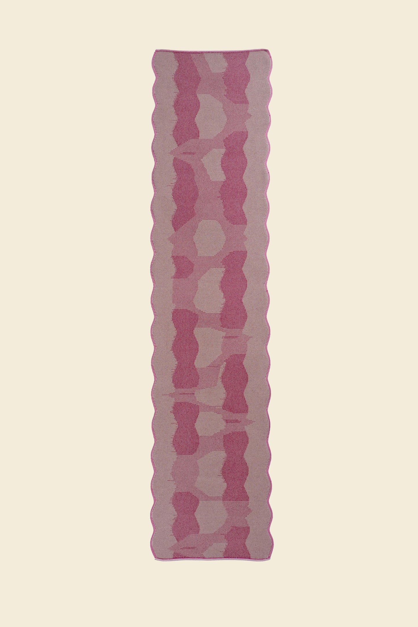 top view of pink knit organic cotton and viscose table runner with abstract pattern and wavy edges