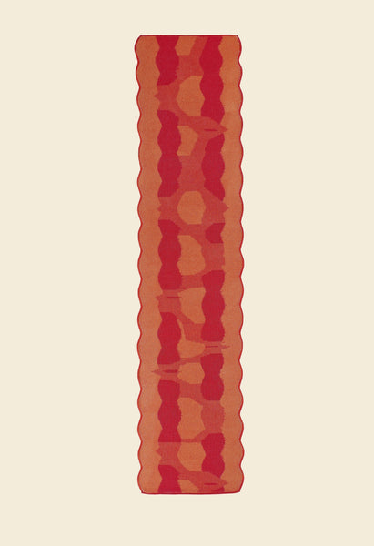 back side of red knit organic cotton and viscose table runner with abstract pattern and wavy edges
