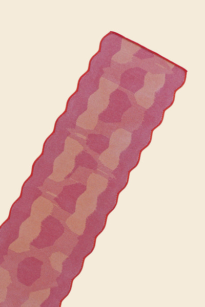 top close-up of red knit organic cotton and viscose table runner with abstract pattern and wavy edges