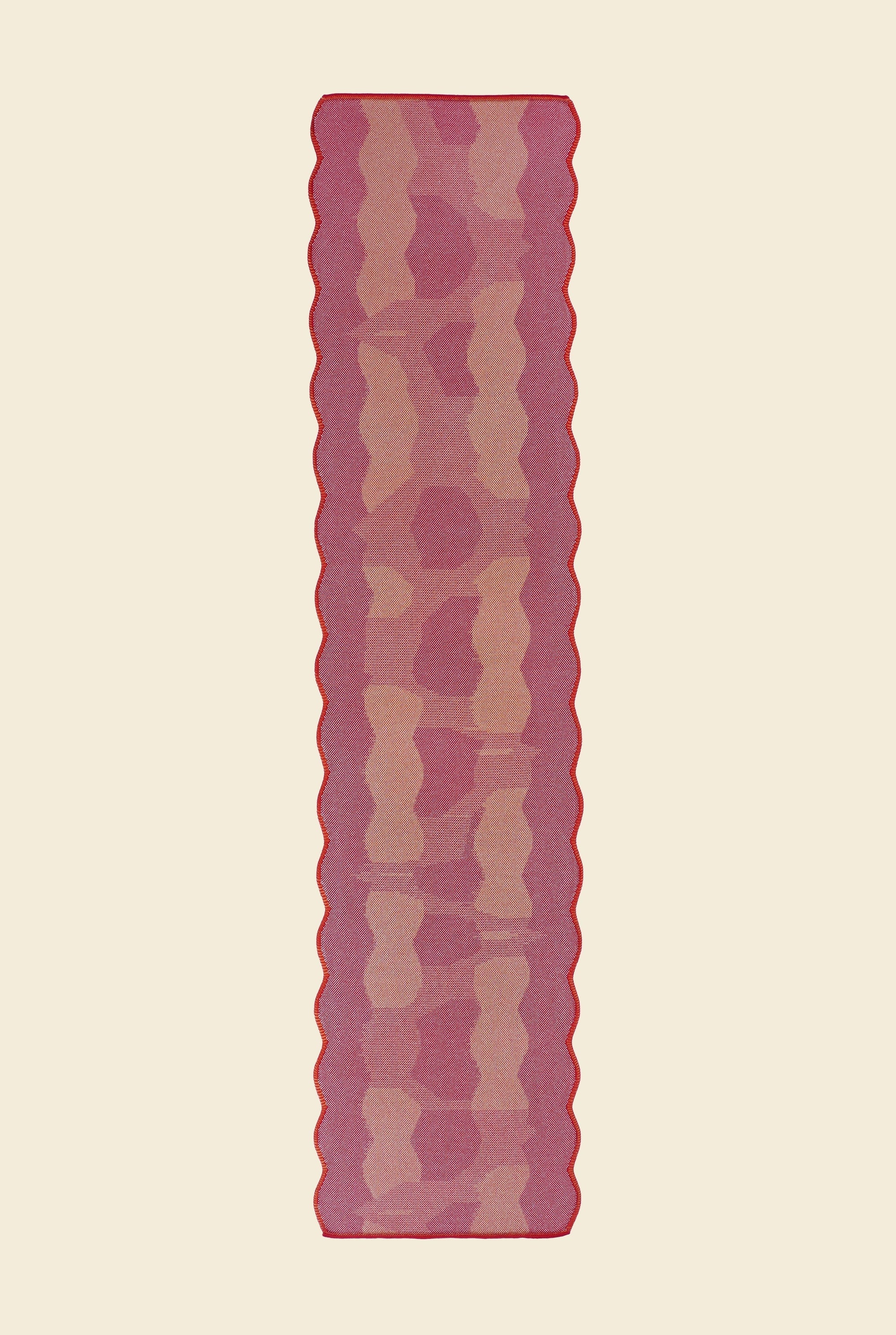 top view of red knit organic cotton and viscose table runner with abstract pattern and wavy edges