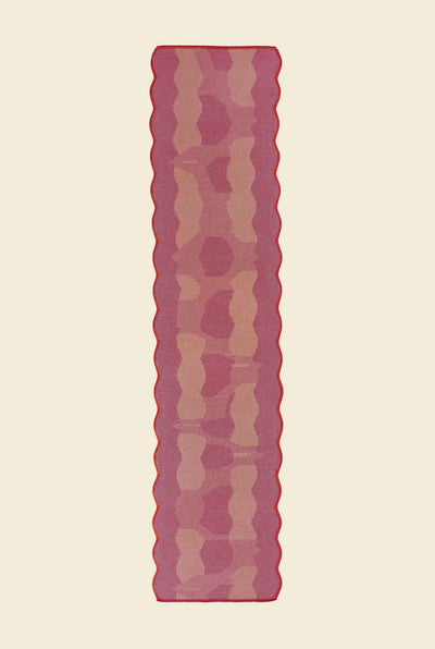 top view of red knit organic cotton and viscose table runner with abstract pattern and wavy edges
