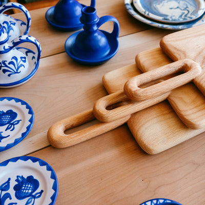 Wooden chain-like object on a wooden surface with blue and white ceramic items in the background. - lifestyle