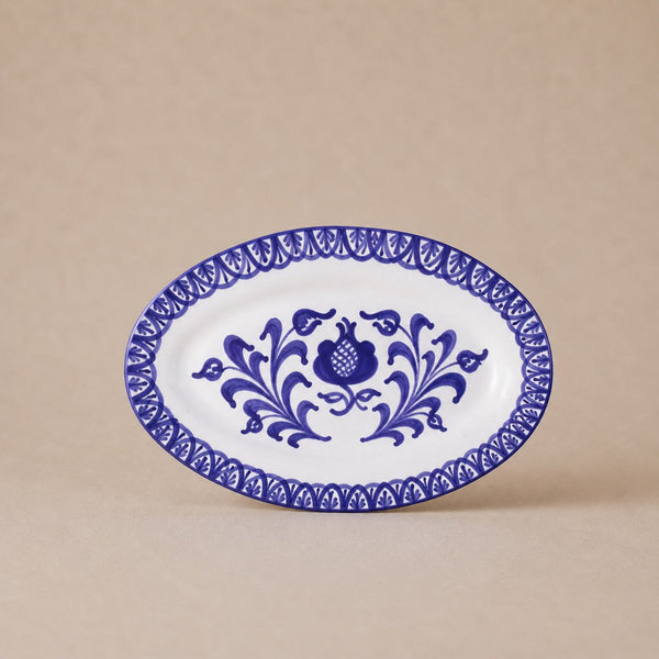 Oval ceramic plate with blue floral design on a beige background