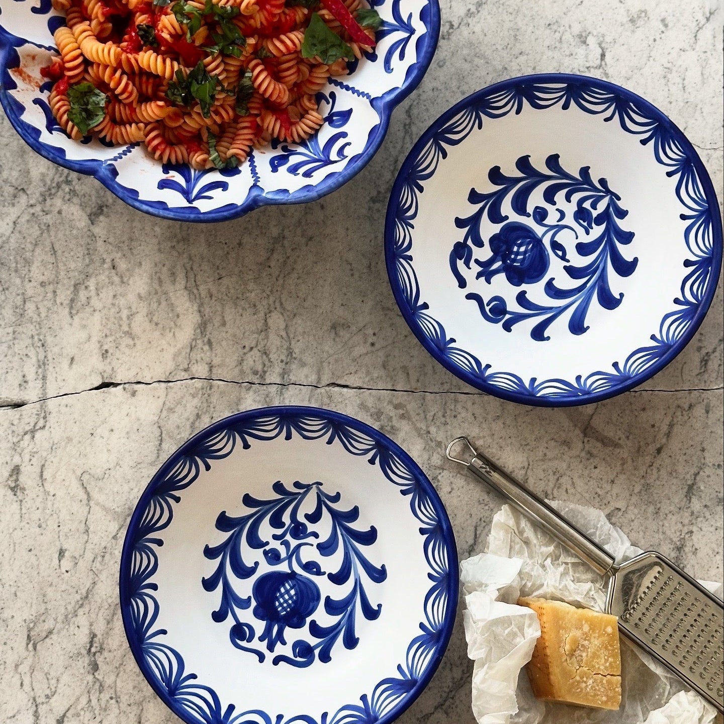 Two blue and white patterned bowls with a dish of pasta on a textured surface. - lifestyle