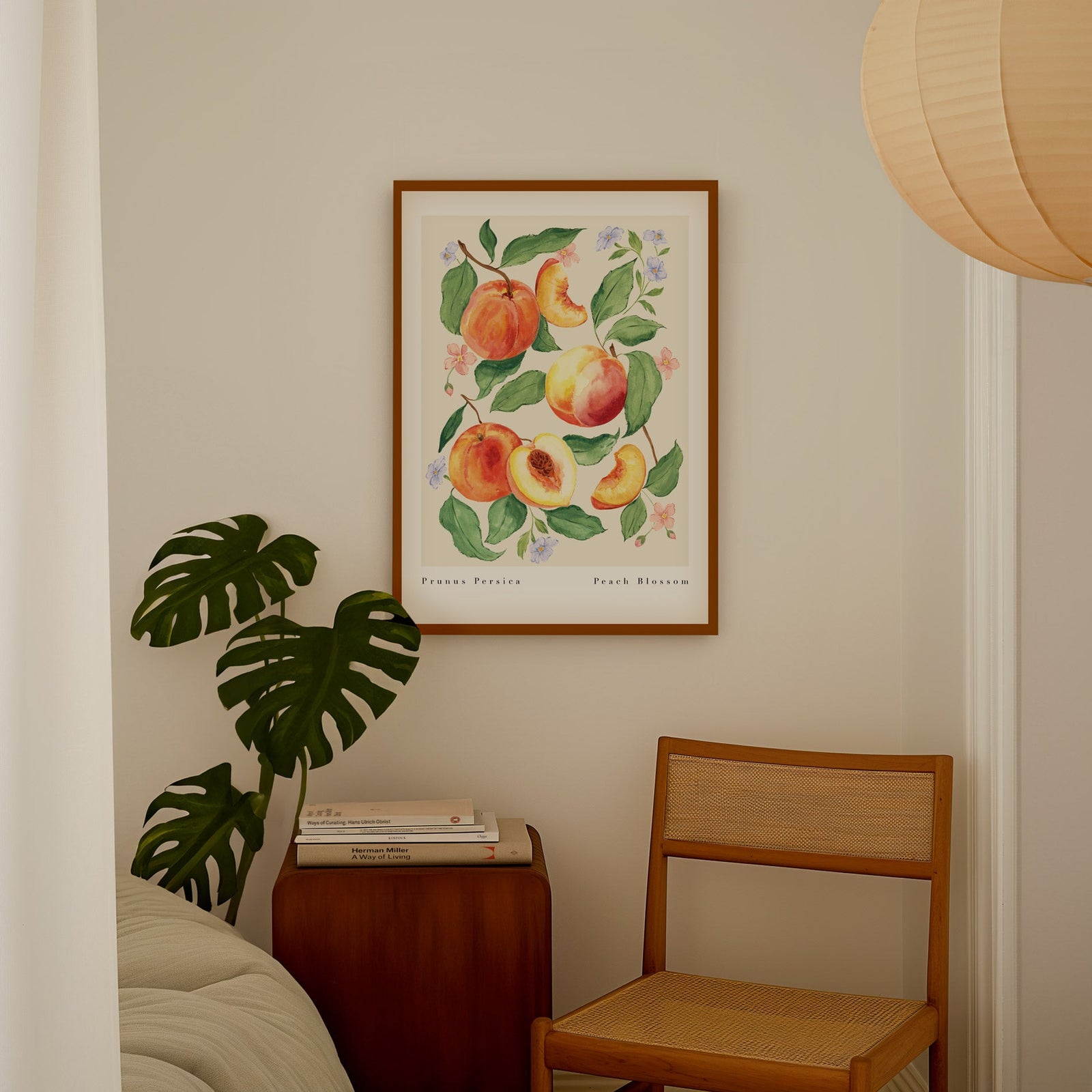 peach art print styled in bedroom by chair and monstera plant 