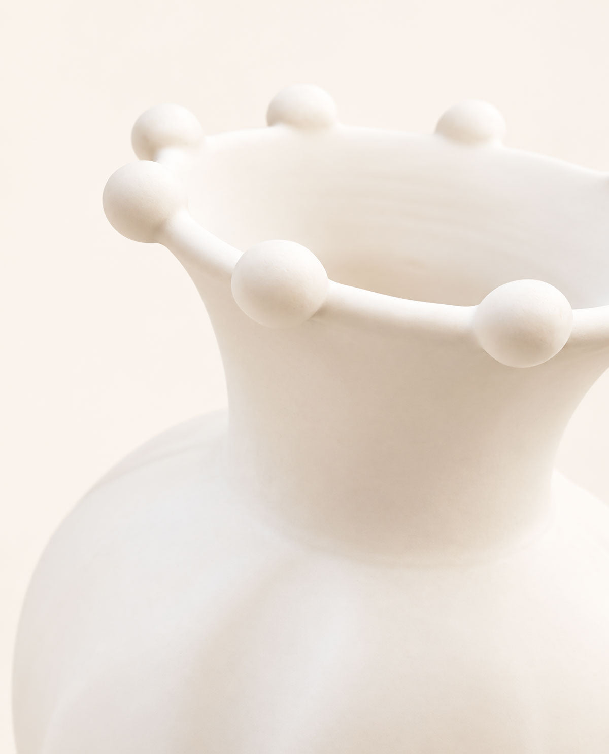 Close-up of the Pearl ceramic vase showing rounded sculptural accents along its flared rim and matte white glaze.