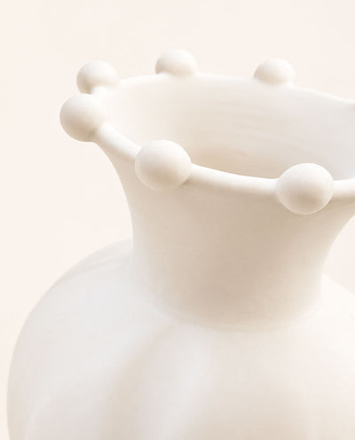 Close-up of the Pearl ceramic vase showing rounded sculptural accents along its flared rim and matte white glaze.