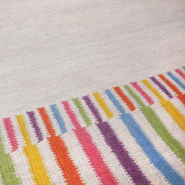 Detail of Rainbow Rug border handwoven in bright colourful shades of yellow, orange, pink, purple, blue and green.