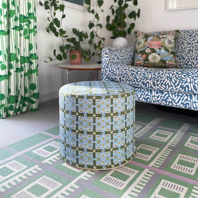Blue and Green living room with Blue Charbagh Fabric pouf, Green flatweave rug, blue printed sofa.