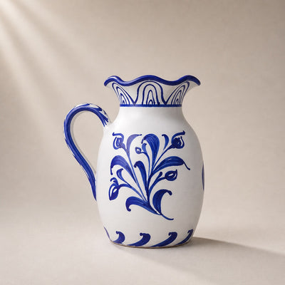 White ceramic pitcher with blue floral patterns on a beige background