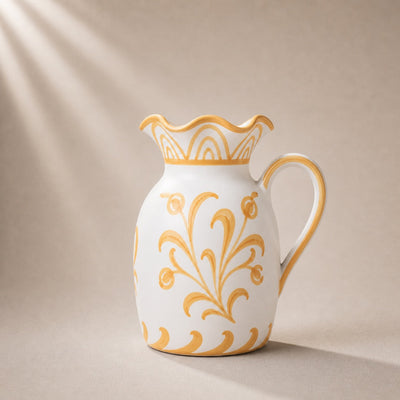 White ceramic pitcher with gold floral patterns on a beige background