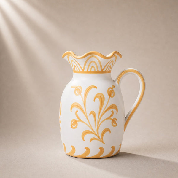 White ceramic pitcher with gold floral patterns on a beige background