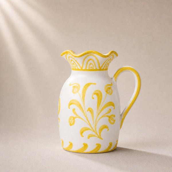 White ceramic pitcher with yellow floral patterns on a beige background