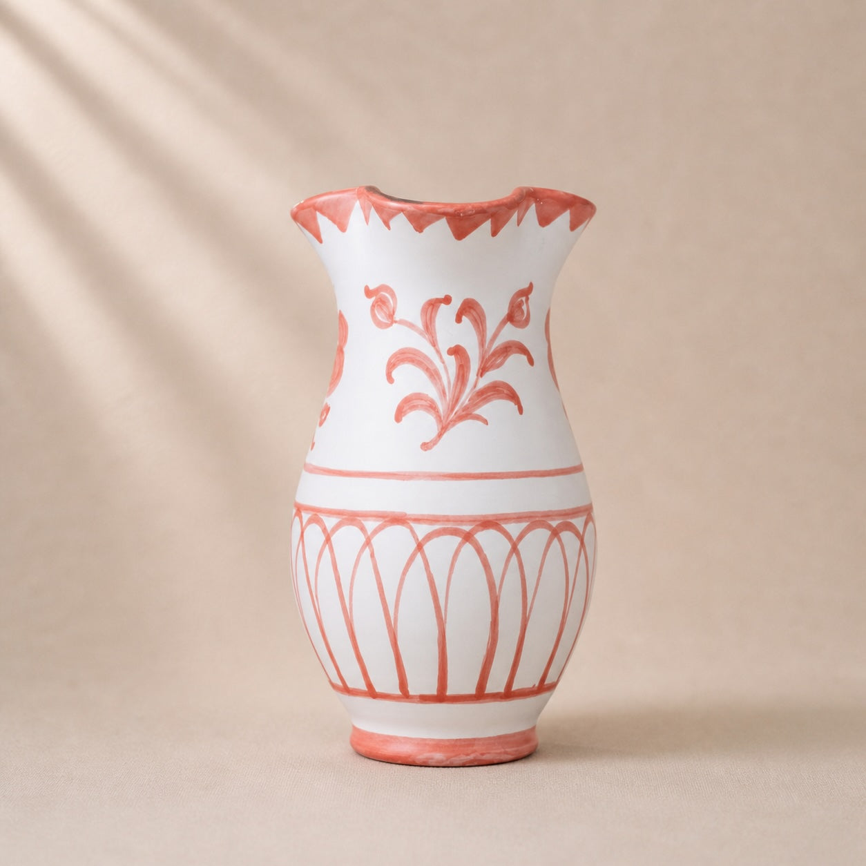 White vase with red floral patterns on a beige background